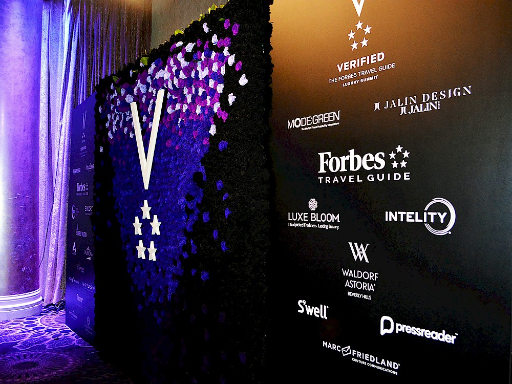 Step and repeat featuring logo constructed from violet, black and white roses